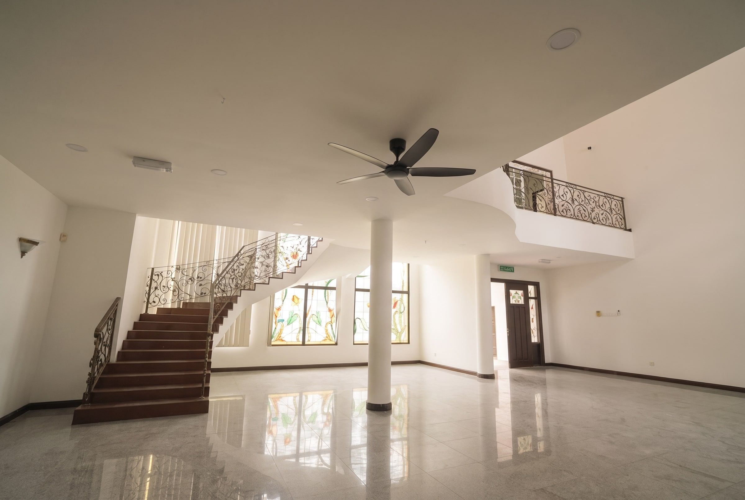Grand double-height foyer with wrought-iron staircase and stained glass