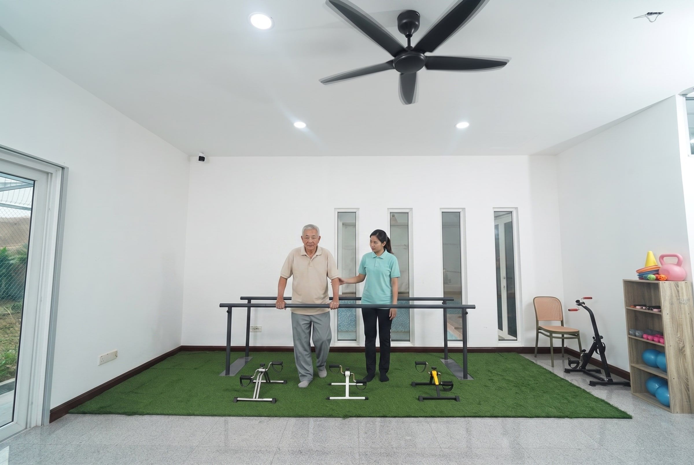 Resident practising walking at the parallel bars with a caregiver